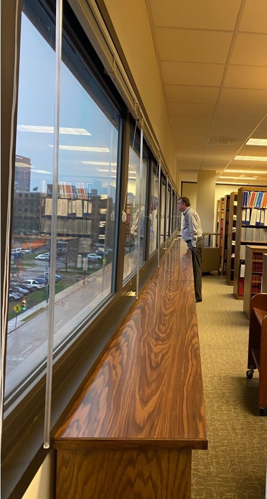 Librarian Anthony Aycock standing and looking out the Library window